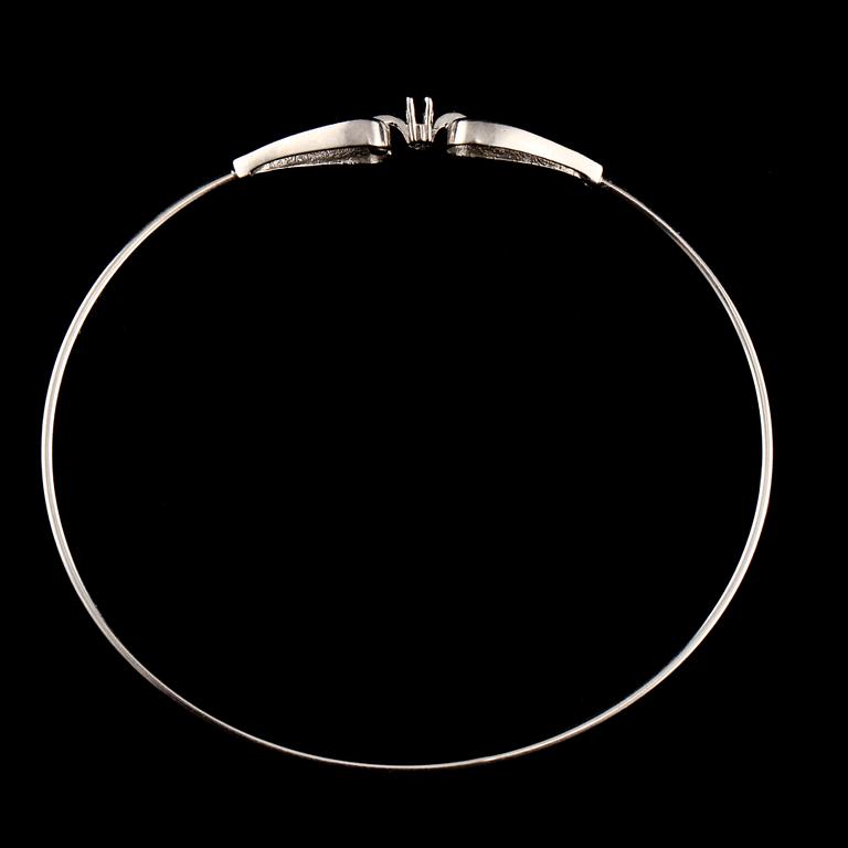ARMRING, 18k vitguld med 2 åttkantslipade diamanter, 0.03 ct samt 2 fasettslipaded blå safirer. Vikt 6 g.