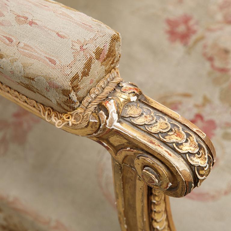 A gilt Louis XVI style armchair from around the year 1900.