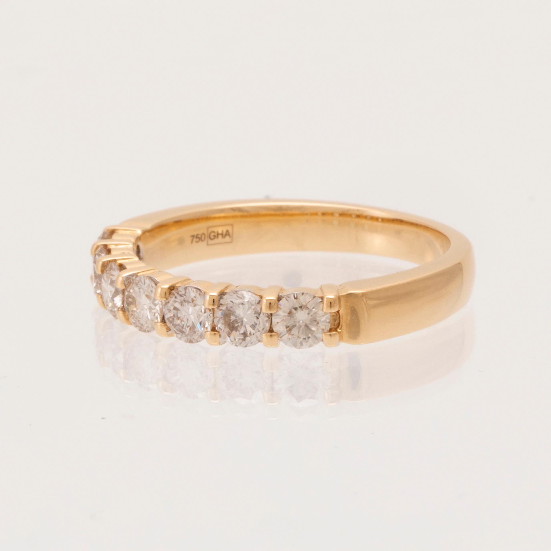An 18K gold half-eternity ring set with round brilliant-cut diamonds.