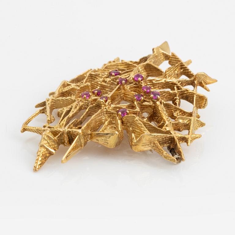 An 18K gold brooch set with faceted rubies.