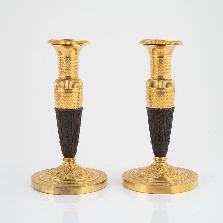 A pair of French Empire gilt and patinated bronze candlesticks, circa 1820's.