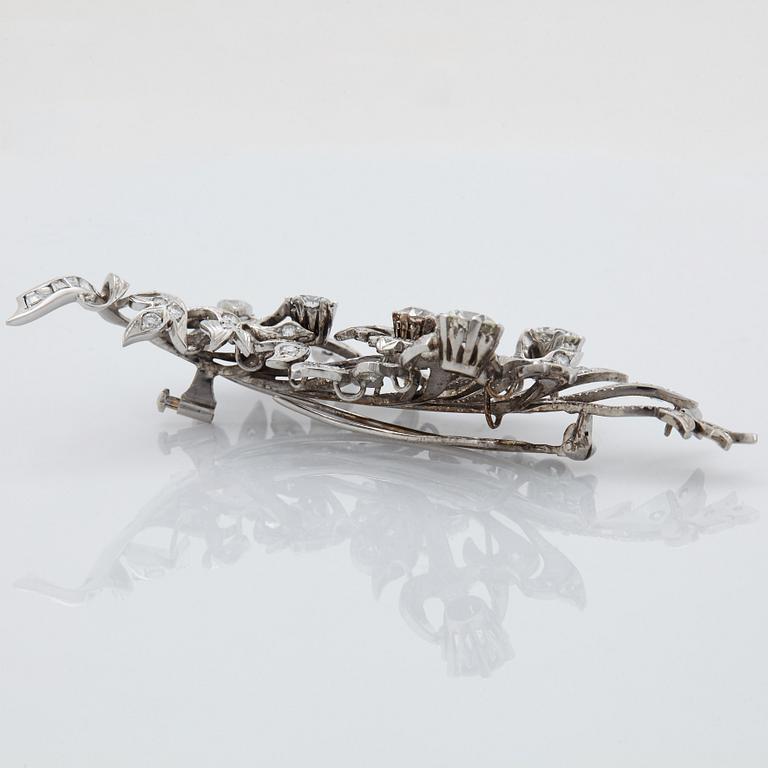 An 18K white gold brooch set with round brilliant-cut diamonds.