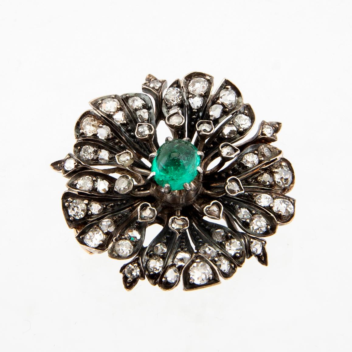 A 14K gold brooch set with a cabochon-cut emerald and old-cut as well as rose-cut diamonds.