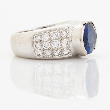 An 18K white gold ring set with an oval faceted sapphire and round brilliant-cut diamonds.