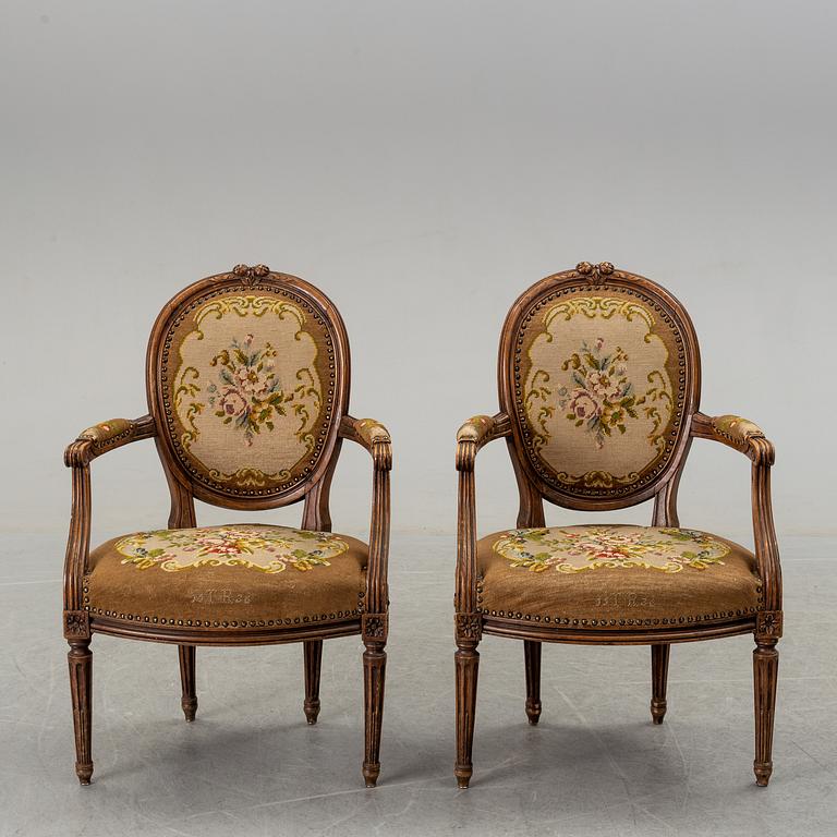 A pair of Louis XVI-style walnut armchairs circa 1900.