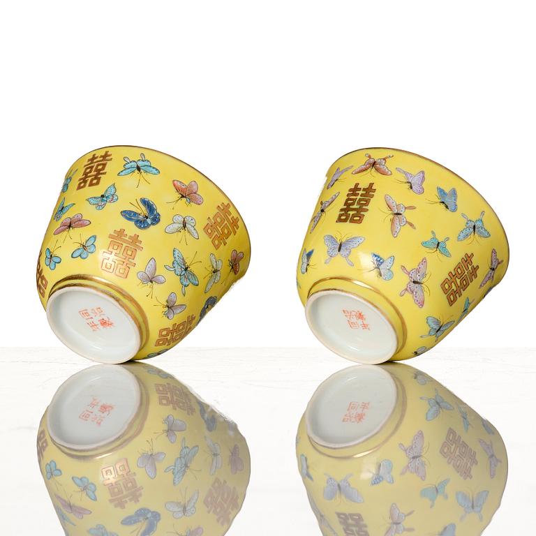 A pair of yellow glazed double happiness cups with butterflies, Qing dynasty, with Tongzhis four character mark to base.