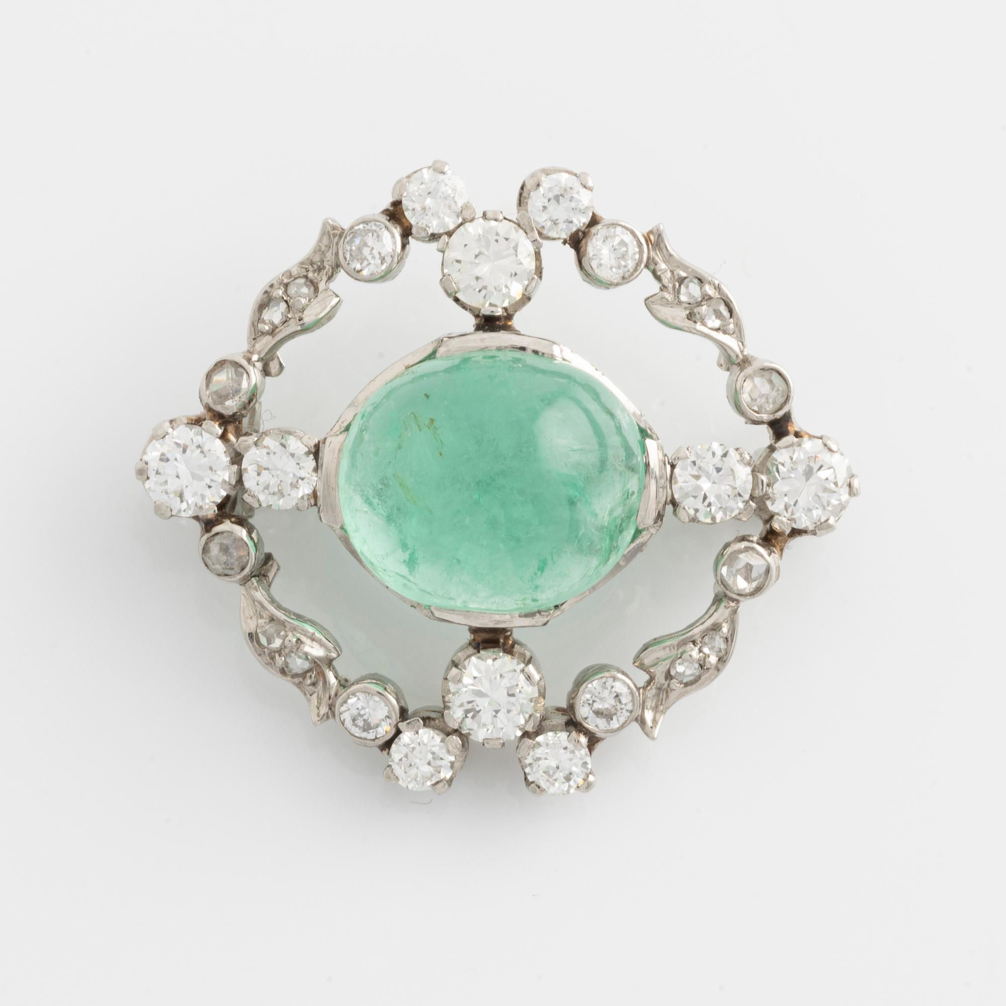 A platinum brooch with a cabochon-cut emerald.