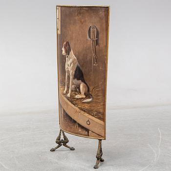A 19th century brass fire shield decorated with paint of hunting dog setter in the stable.