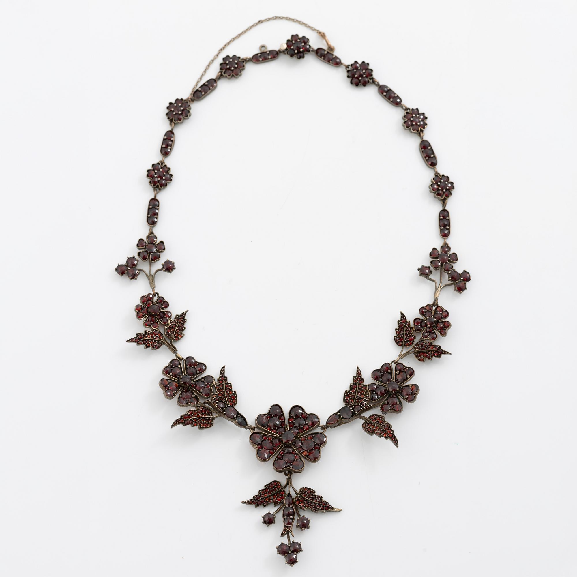 Garniture, necklace/bracelet and earrings in silver with garnets in the form of floral motifs, around the turn of the 20th century.