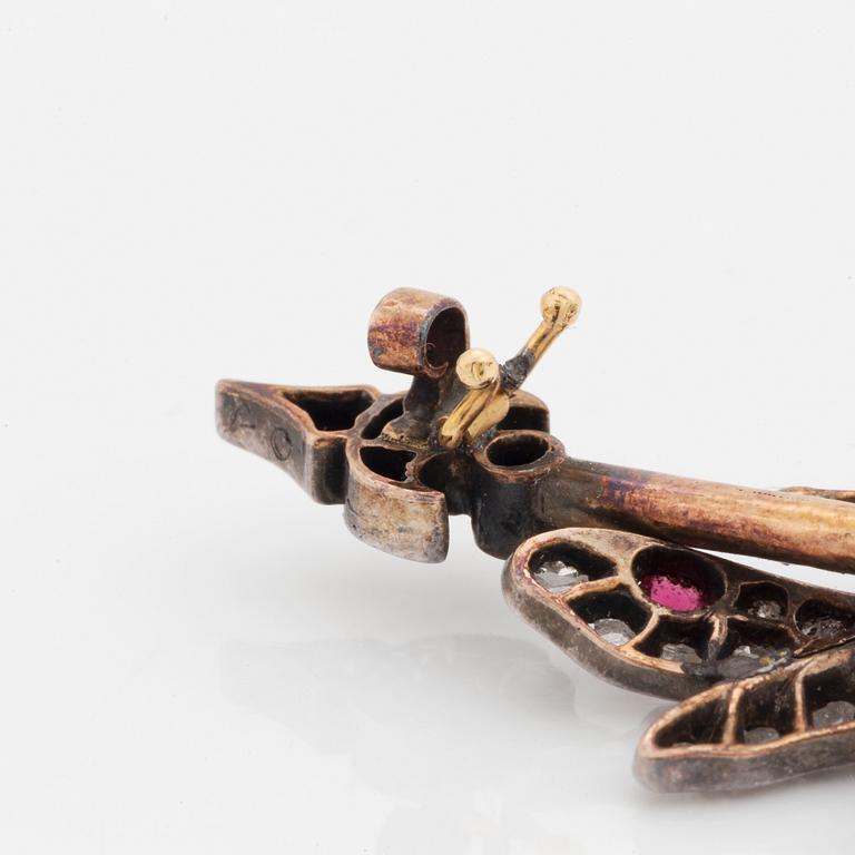A silver and gold brooch set with rose-cut diamonds and cabochon-cut rubies.