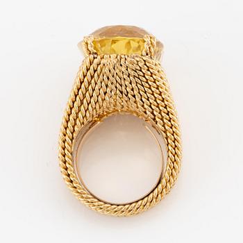 A Sterlé 18K gold ring set with a faceted oval yellow sapphire.