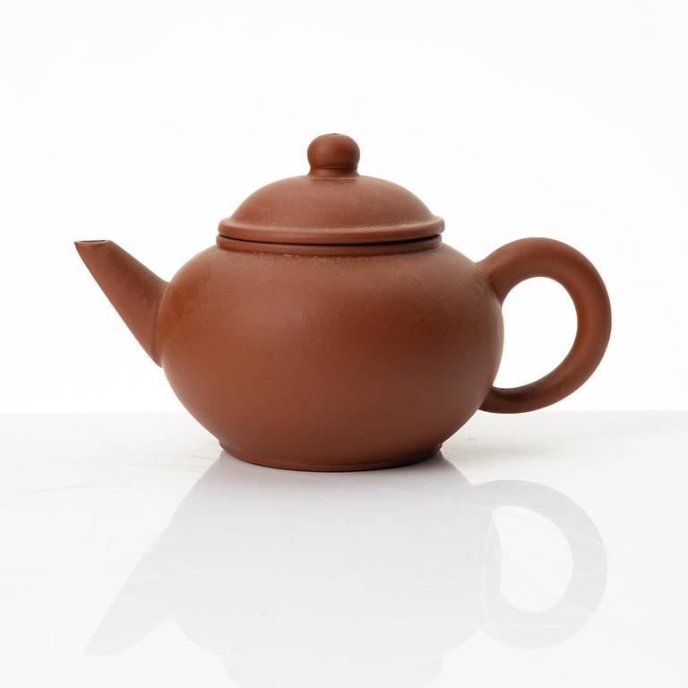 A six part red yixing Gongfu set; teapot, four cups and a tray, China, 1980s.