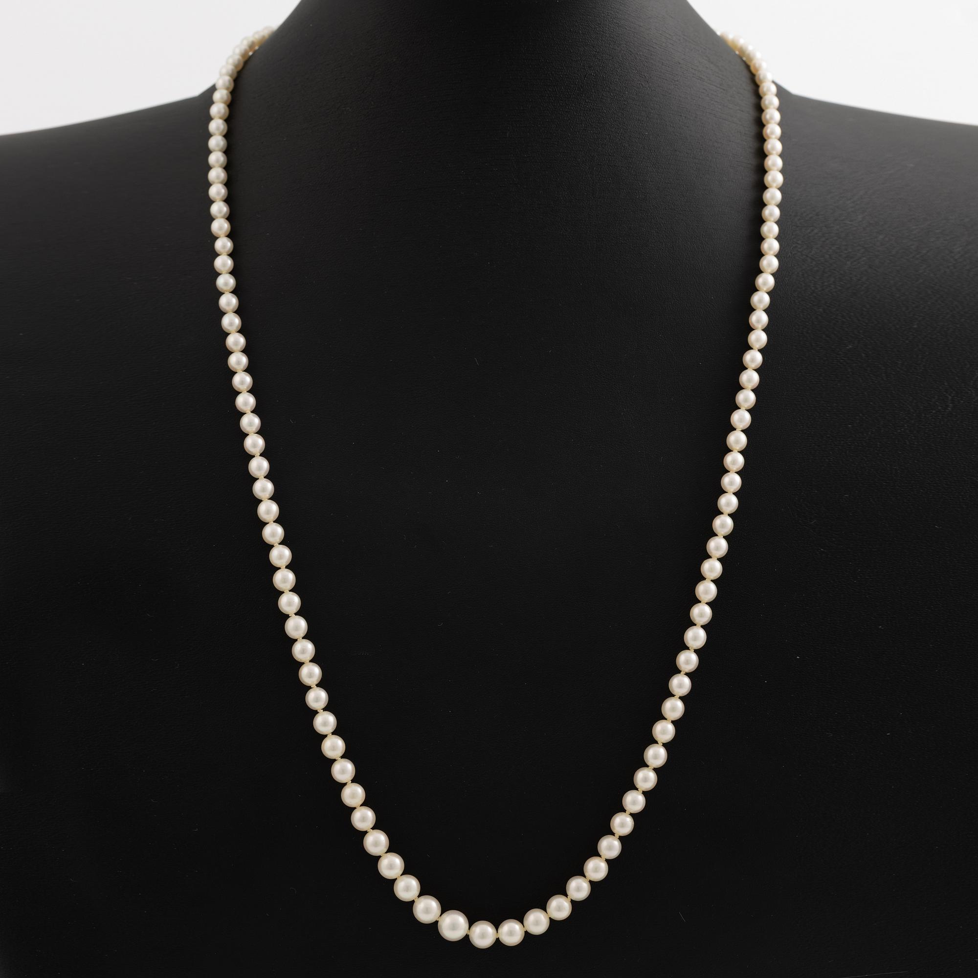 Necklace with graduated cultured pearls, with a clasp in 18K white gold set with an emerald.