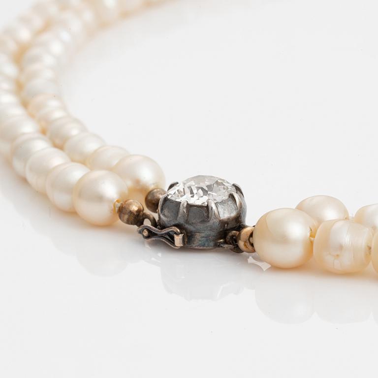 A two strand natural pearl necklace with a silver  clasp set with an old-cut diamond.
