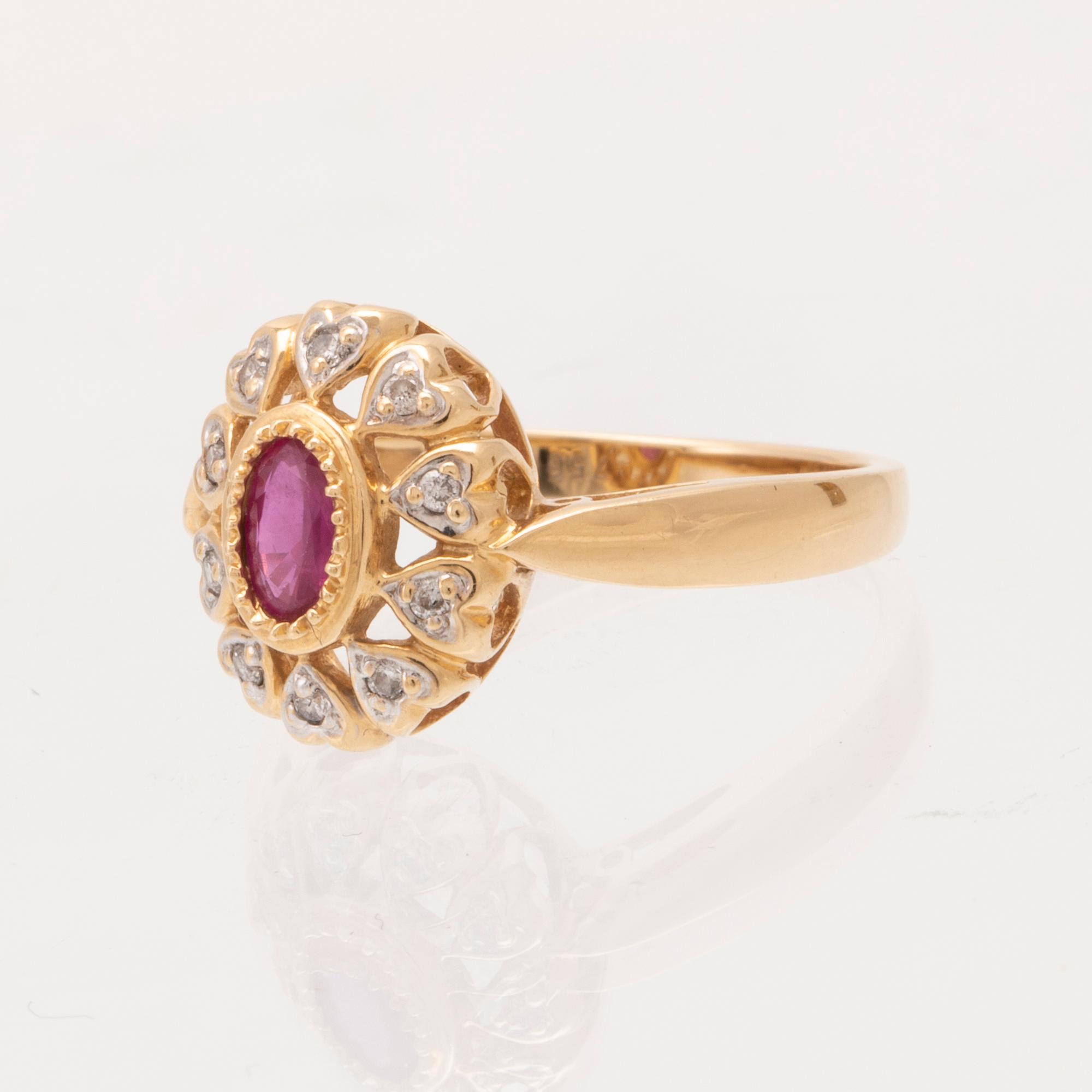An 18K gold ring set with an oval brilliant cut ruby and round brilliant cut diamonds.