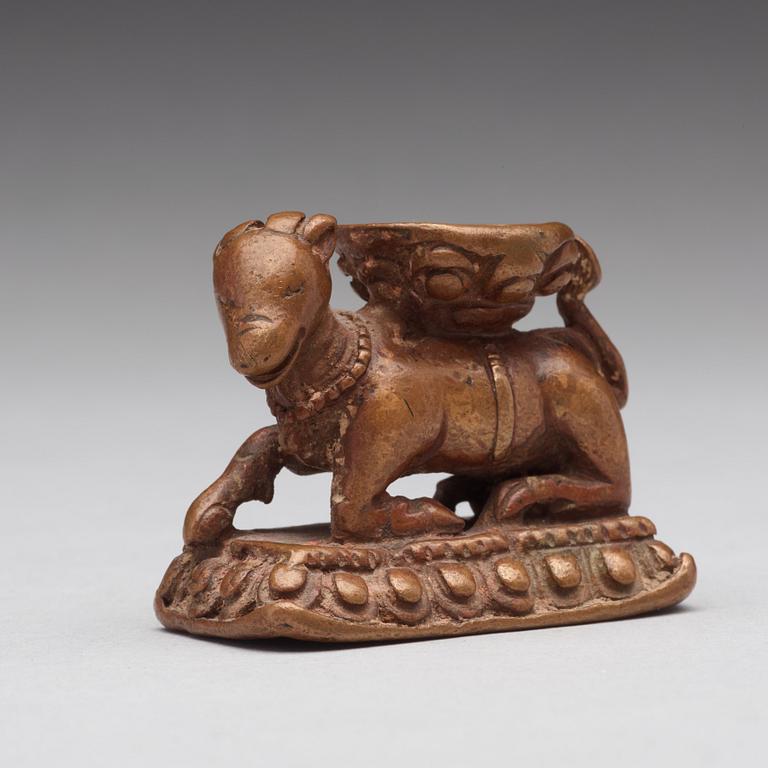 A gilt copper alloy figure of a reclining animal with a lotus throne on its back, Nepal, 15th Century.