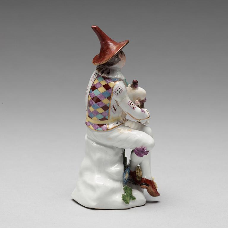 A porcelain figure of harlekin playing the bagpipe, circa 1900.