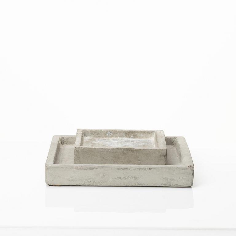 A mixed lot comprising a pair of limestone bookends, a bookshelf and two plates in concrete.