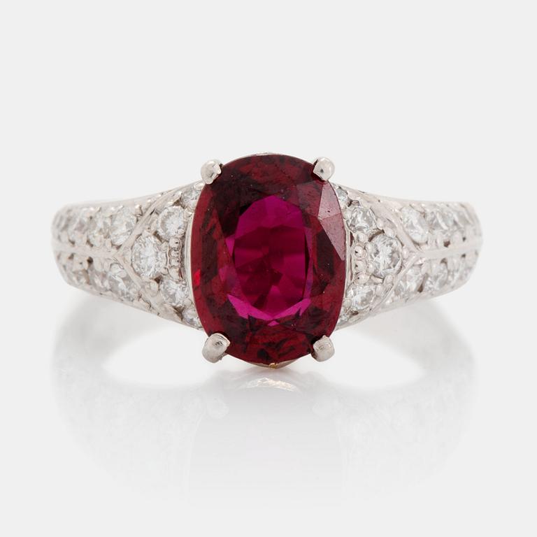 A platinum ring set with a faceted ruby and round brilliant-cut diamonds.