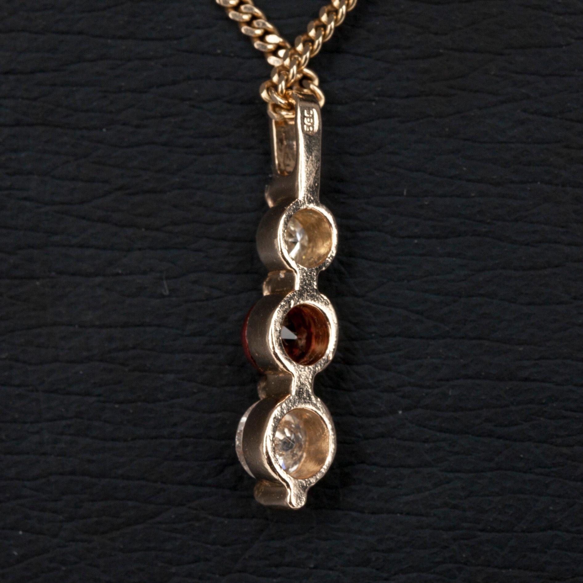 HÄNGE I KED, guld 14K, 2 diamanter tot. 0,34 ct, och en granat 0,32 ct. Vikt 4,1 g.