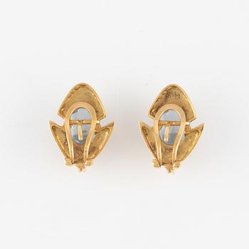 A pair of 18K gold earrings with faceted blue stones.