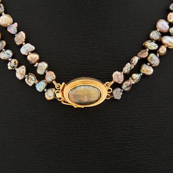 Necklace of cultured pearls with a clasp of 18K gold and cabochon-cut likely tourmaline.