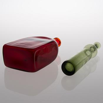 Two glass bottles. A green 'Neptuna' bottle designed by Nanny Still in 1964 and a red bottle from Riihimäen Lasi oy.