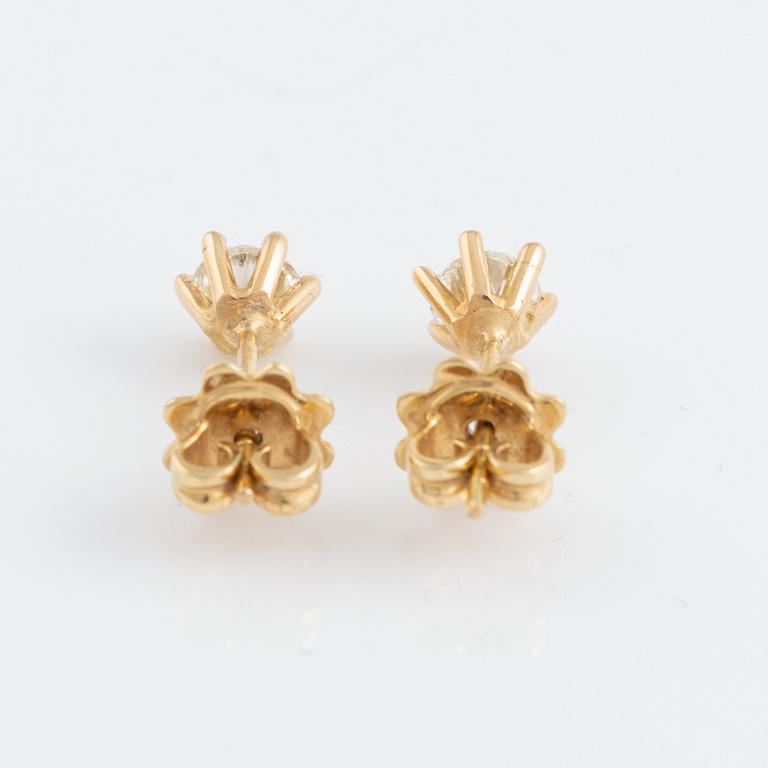 A pair of gold earrings set with round brilliant-cut diamonds.