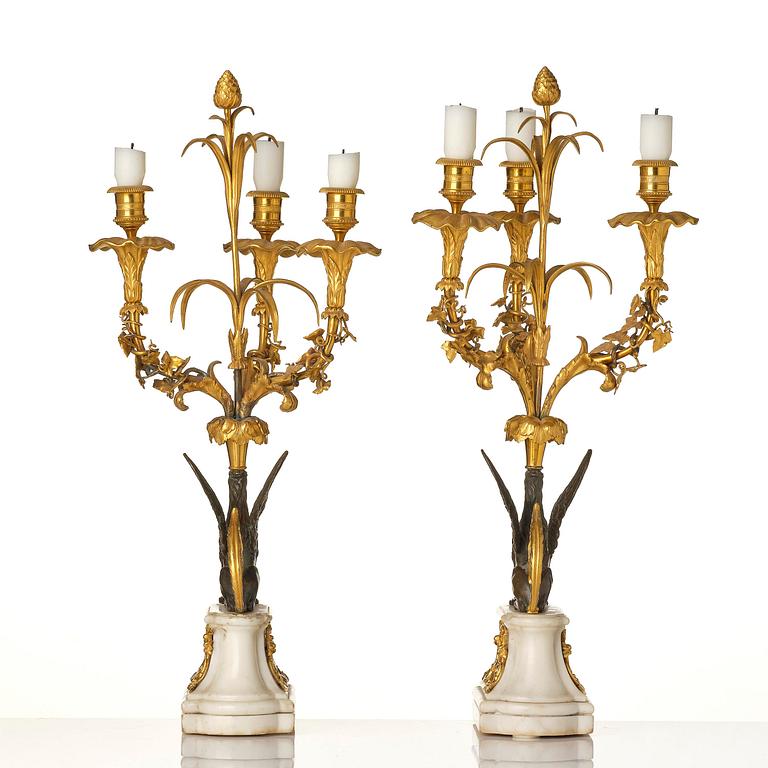 A pair of three-light Louis XVI patinated and ormolu candelabra in the manner of François Rémond, late 18th century.
