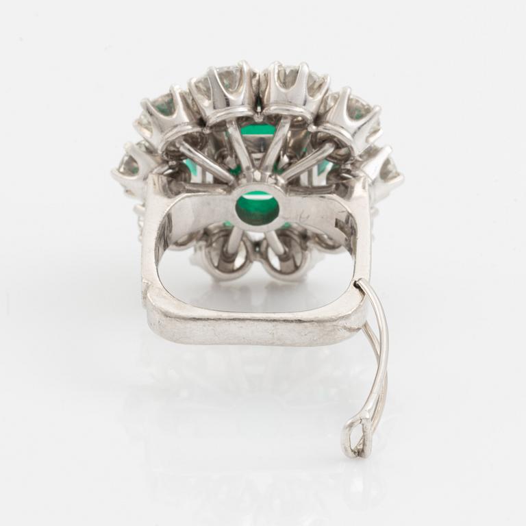 A WA Bolin platinum ring set with a step-cut emerald and round brilliant-cut diamonds.