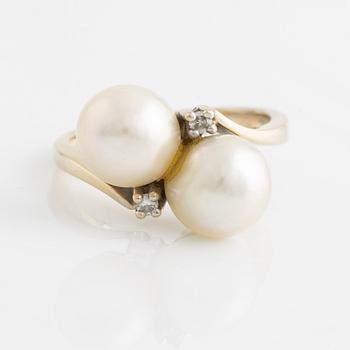 An 18K gold ring set with cultured pearls and white stones.