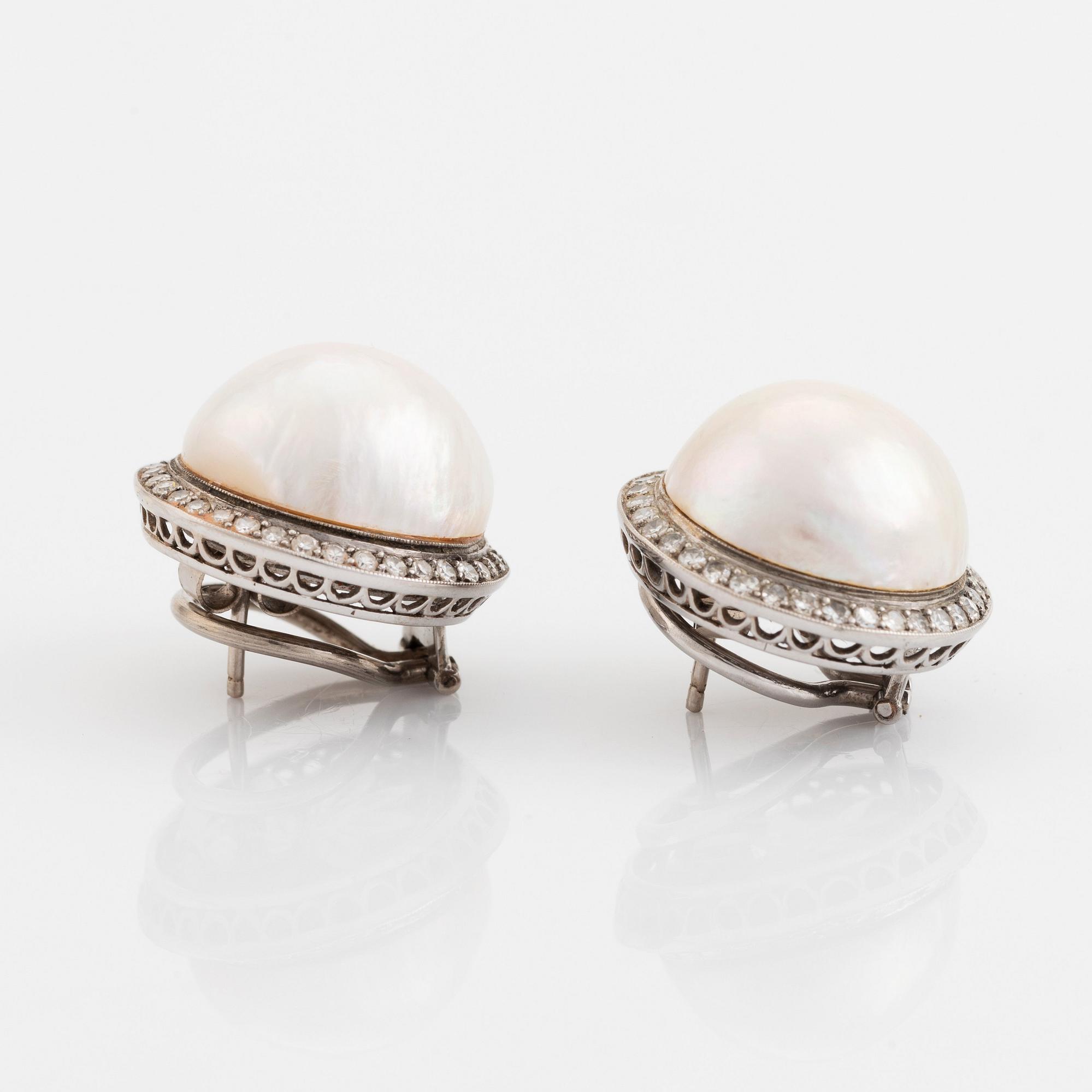 A pair of 18K white gold earrings set with cultured mabe pearls and round brilliant-cut diamonds.
