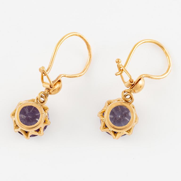 A pair of earrings in 18K gold with purple stones.