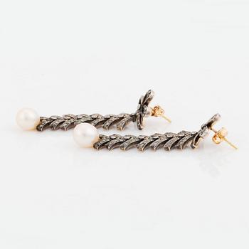 A pair of silver and 18K gold earrings with cultured pearls and set with eight-cut diamonds.