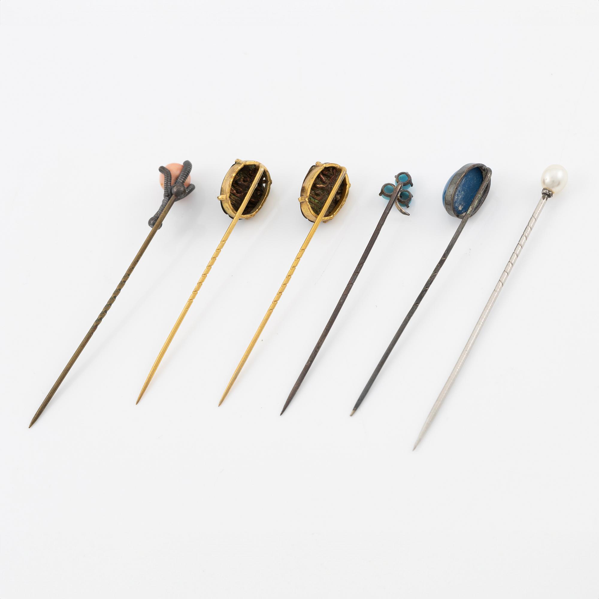 Six brooch pins in various designs and materials.