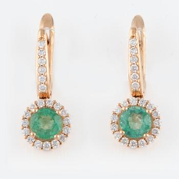 A pair of earrings with faceted emeralds and round brilliant-cut diamonds.