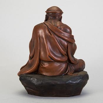 A Japanese earthenware seated figure of a man holding a pagoda, 20th century.