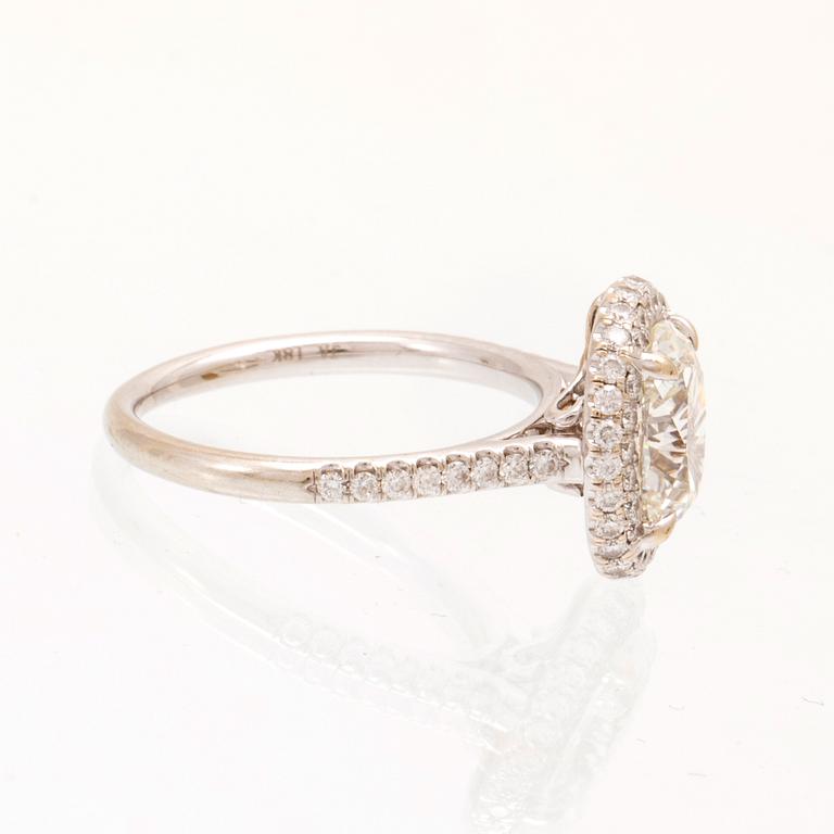 An 18K white gold ring by James Allen, set with an oval brilliant cut diamond in a halo of round brilliant cut diamonds.
