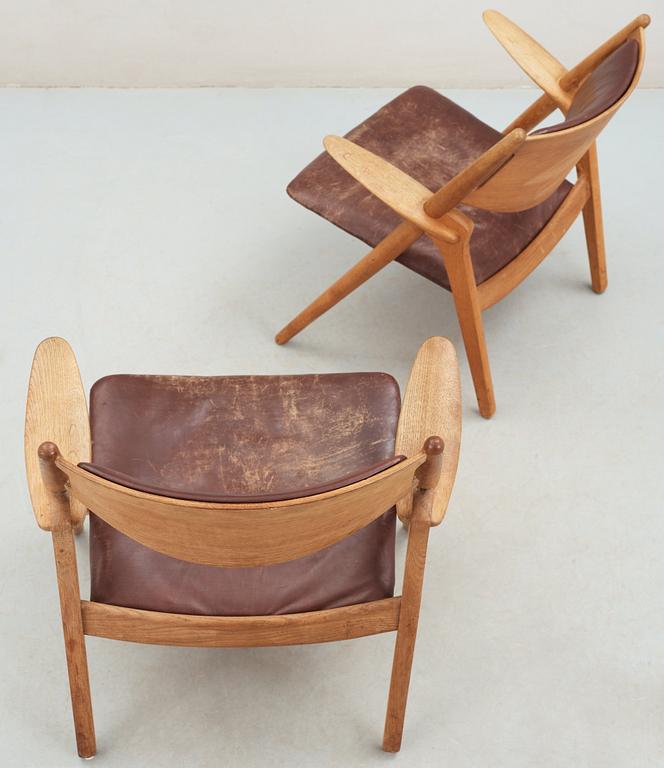 A pair of Hans J Wegner oak and brown leather easy chairs, Carl Hansen & Son, Denmark 1950's-60's.