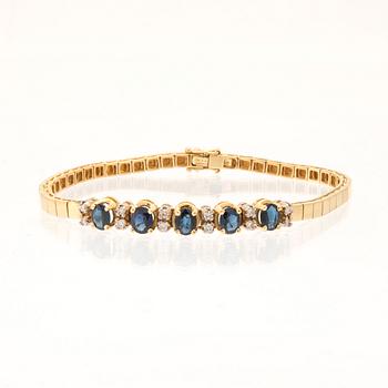 An 18K white and yellow gold bracelet set with oval-cut sapphires and round brilliant-cut diamonds.