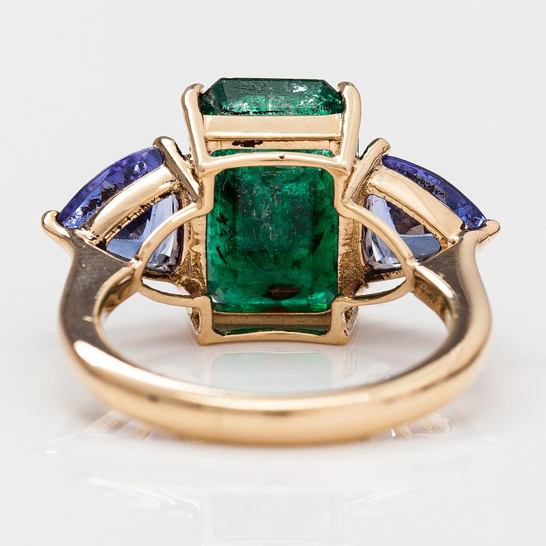 A 14K gold ring with tanzanites and a ca 5.80 ct emerald.