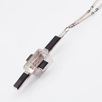 Wiwen Nilsson, hängsmycke i form av ett kors i sterlingsilver med fasettslipad bergkristall och onyx, Lund 1938.