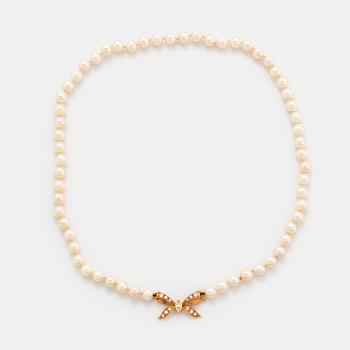 466. A cultured pearl necklace with a bow clasp in 18K gold set with round brilliant-cut diamonds.