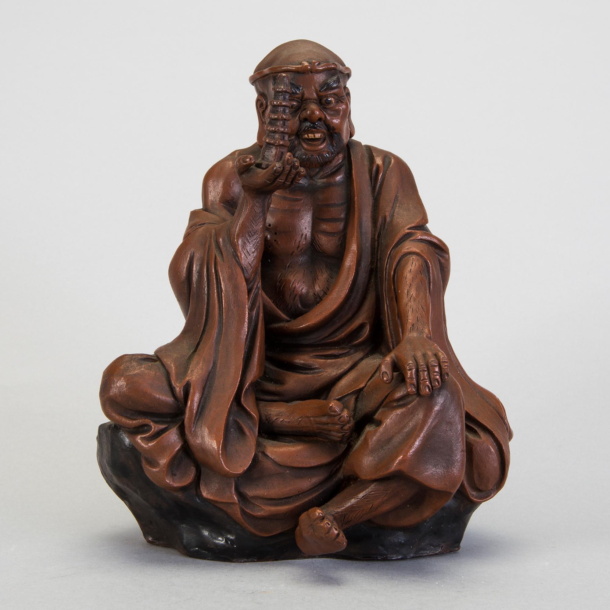 A Japanese earthenware seated figure of a man holding a pagoda, 20th century.