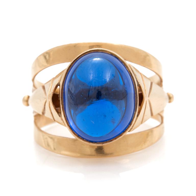 A ring set with an oval, cabochon-cut, synthetic, blue spinel.