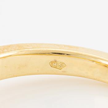 A ring in 18K gold with an oval brilliant-cut diamond and two round brilliant-cut diamonds.