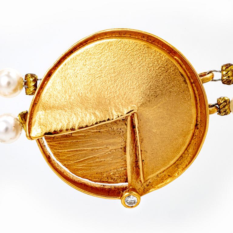 A necklace of cultured pearls and pendant in 18K gold with a brilliant cut diamond.