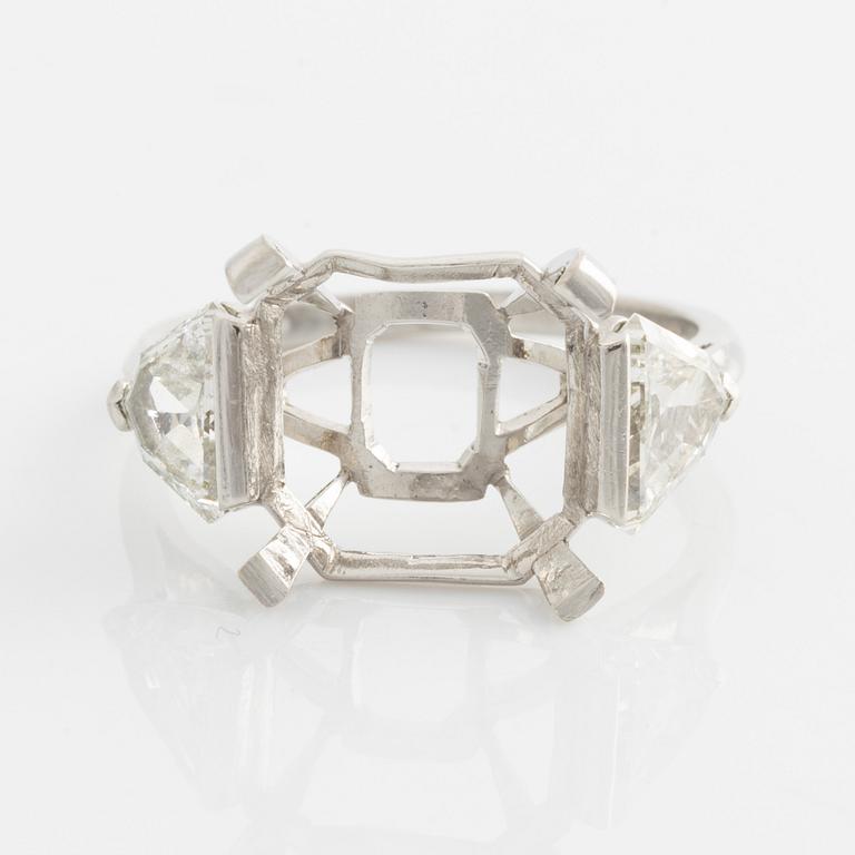 A platinum ring with and empty setting and with two triangular step cut diamonds.