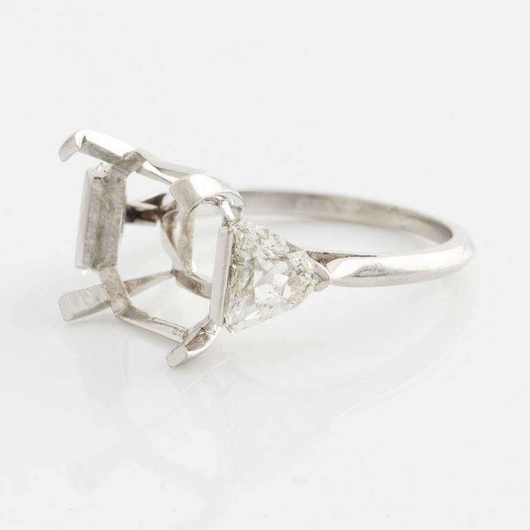 A platinum ring with and empty setting and with two triangular step cut diamonds.