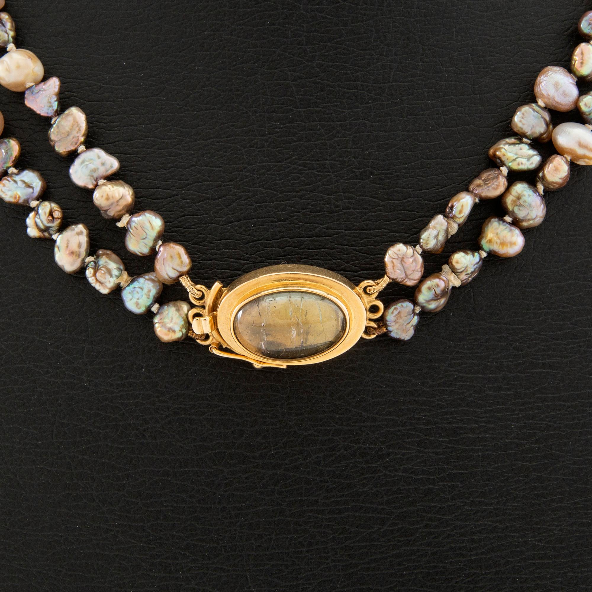 Necklace of cultured pearls with a clasp of 18K gold and cabochon-cut likely tourmaline.